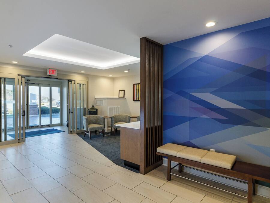 A hotel lobby with a reception desk, seating area, and a glass door entrance.