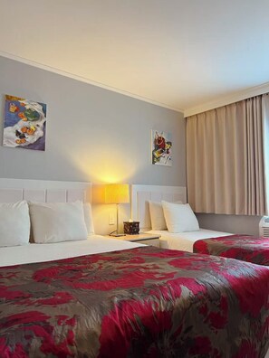 A hotel room with two beds, a nightstand, a lamp, and two wall art pieces. - Flushing Central Hotel 88 (Flushing)