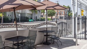An outdoor patio area with metal tables and chairs, surrounded by a wrought iron fence. - Knights Inn Downtown Los Angeles (Los Angeles)