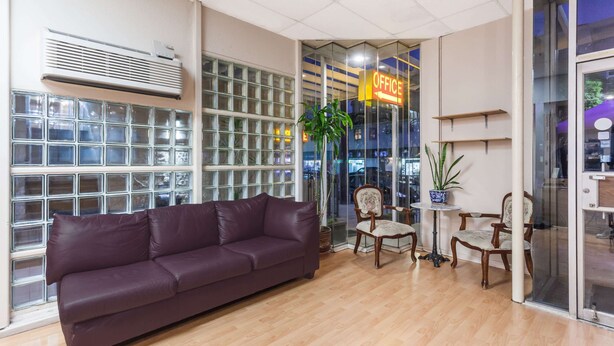 A modern office space with a leather sofa, wooden chairs, and a glass wall with an 'OFFICE' sign. - Knights Inn Downtown Los Angeles (Los Angeles)