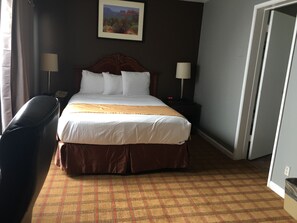 A hotel room with a large bed, two bedside lamps, a nightstand, a chair, and a painting on the wall. - Knights Inn Downtown Los Angeles (Los Angeles)