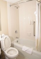 Un baño con inodoro, bañera, ducha y barras de apoyo.