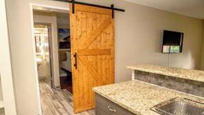 A kitchen with a granite countertop, a wooden sliding door, and a built-in sink.