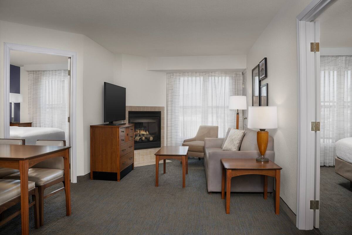 Habitación de hotel con sofá, televisión, chimenea y zona de comedor.