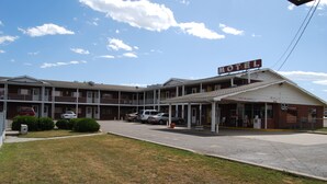 A motel with a two-story structure, a covered parking area, and a clear sky. - Budget Host 254 Inn Loveland (Loveland)