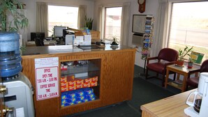 A motel reception desk with a sign indicating office hours and coffee service times. - Budget Host 254 Inn Loveland (Loveland)