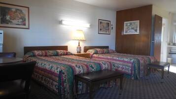 Une chambre d’hôtel avec deux lits, une petite table, une chaise et une lampe.