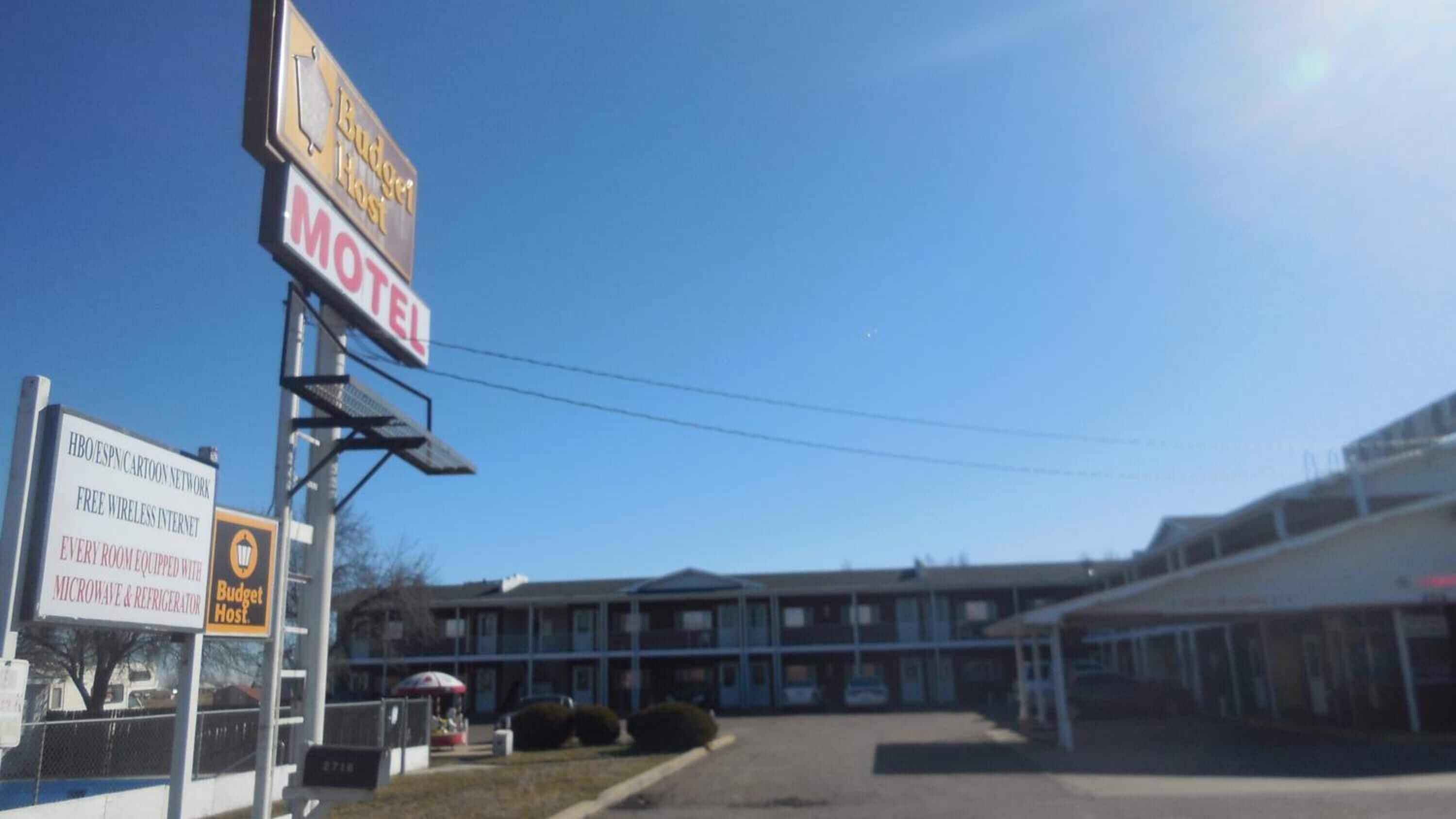 A motel with signs indicating free wireless internet, every room equipped with a microwave and refrigerator, and a Budget Host sign.