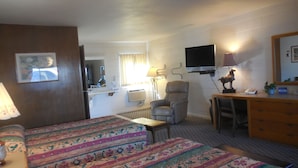 A hotel room with two beds, a desk, a chair, a TV, a lamp, and a mirror. - Budget Host 254 Inn Loveland (Loveland)