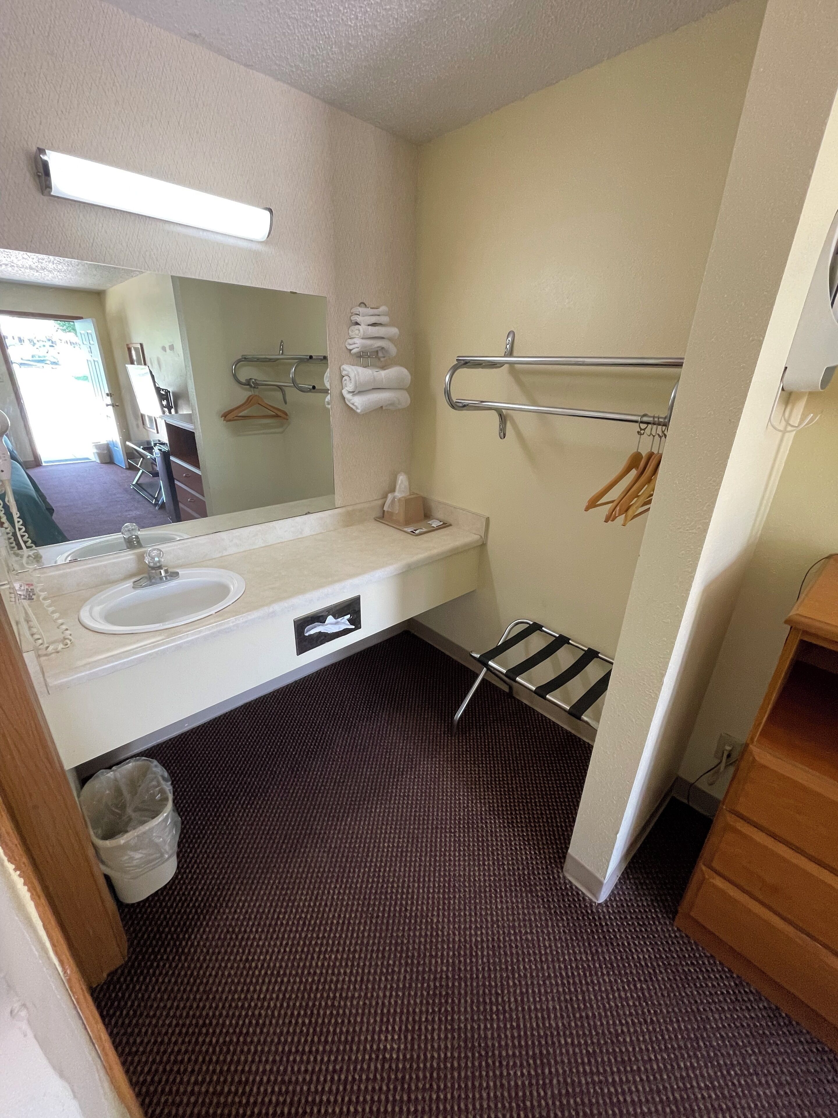 A bathroom with a sink, mirror, towel rack, and a hand dryer.