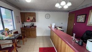 Una cocina compacta con armarios de madera, un tapete rojo y una zona de comedor con sillas de madera.