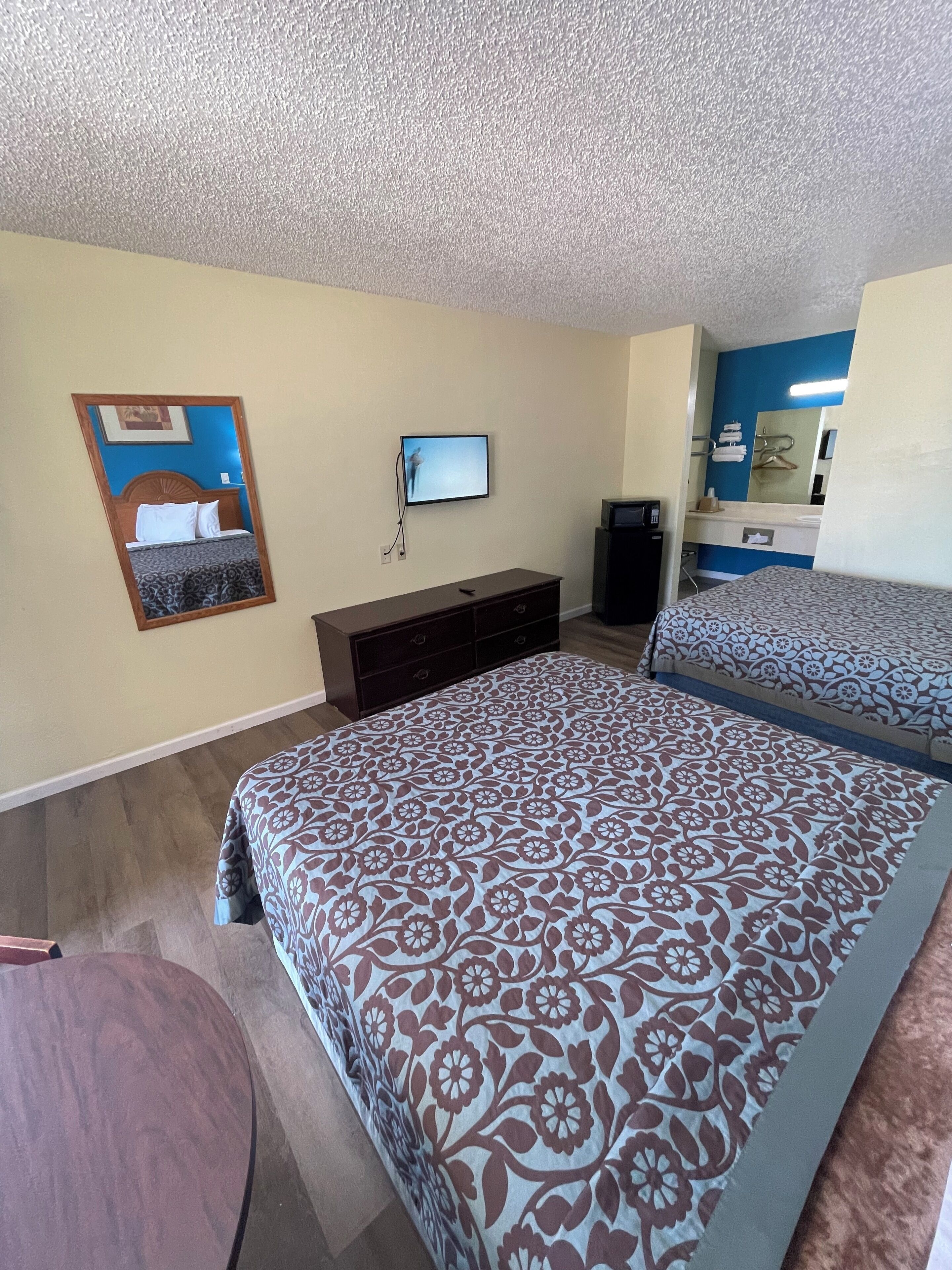 A hotel room with a large bed, a TV mounted on the wall, a dresser, and a mirror.