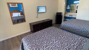 A hotel room with a large bed, a TV mounted on the wall, a dresser, and a mirror.