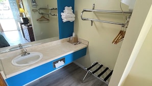 Un baño con lavamanos, espejo, toallero y un pequeño cubo de basura.