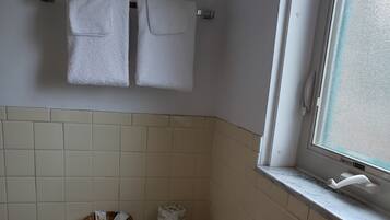 A small bathroom with a toilet, a window, and a towel rack with two towels.