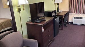 Une chambre d’hôtel équipée d’un bureau, d’une chaise, d’une lampe, d’un climatiseur et d’un lit.