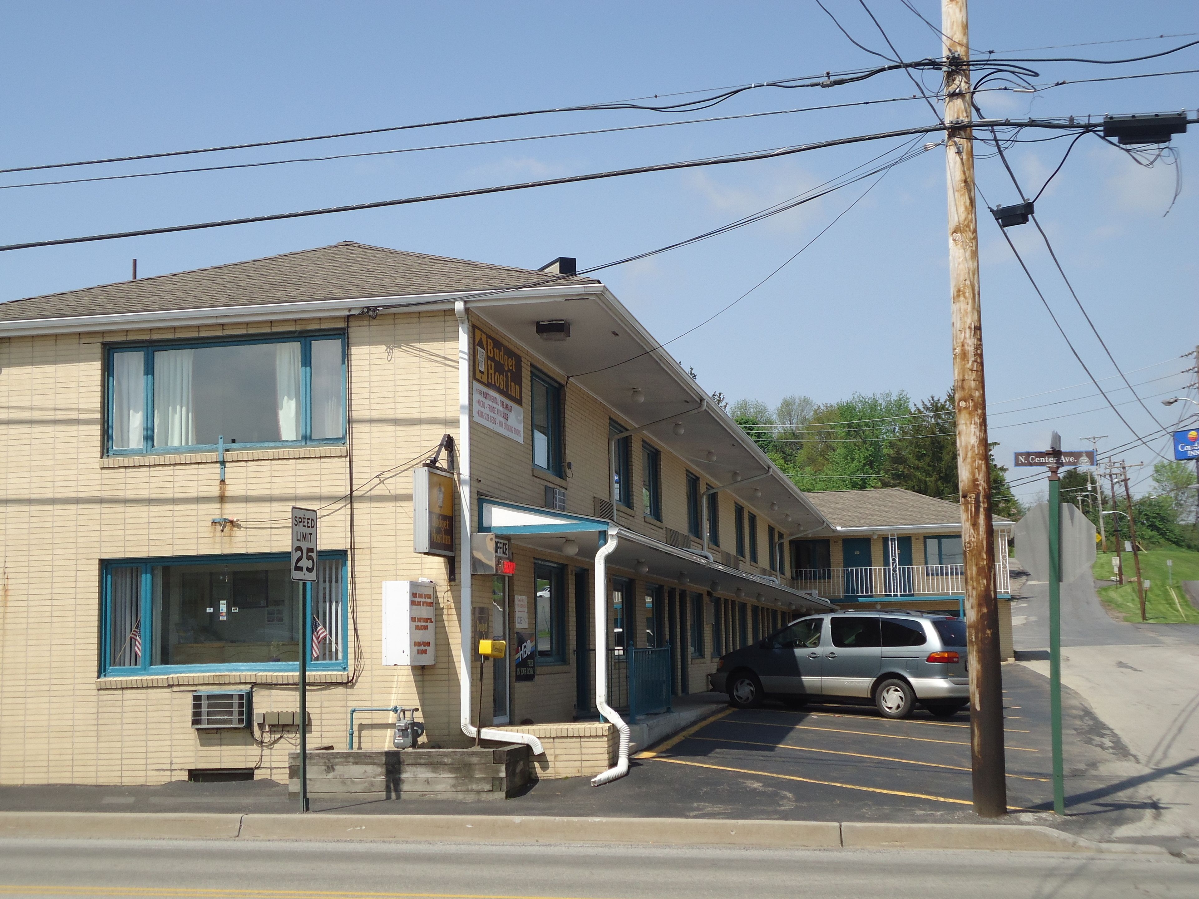 A motel with a covered parking area, a speed limit sign, and a sign for 'Budget Motel'.