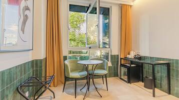 A small kitchen with a dining area, a window with curtains, and a green tiled backsplash.