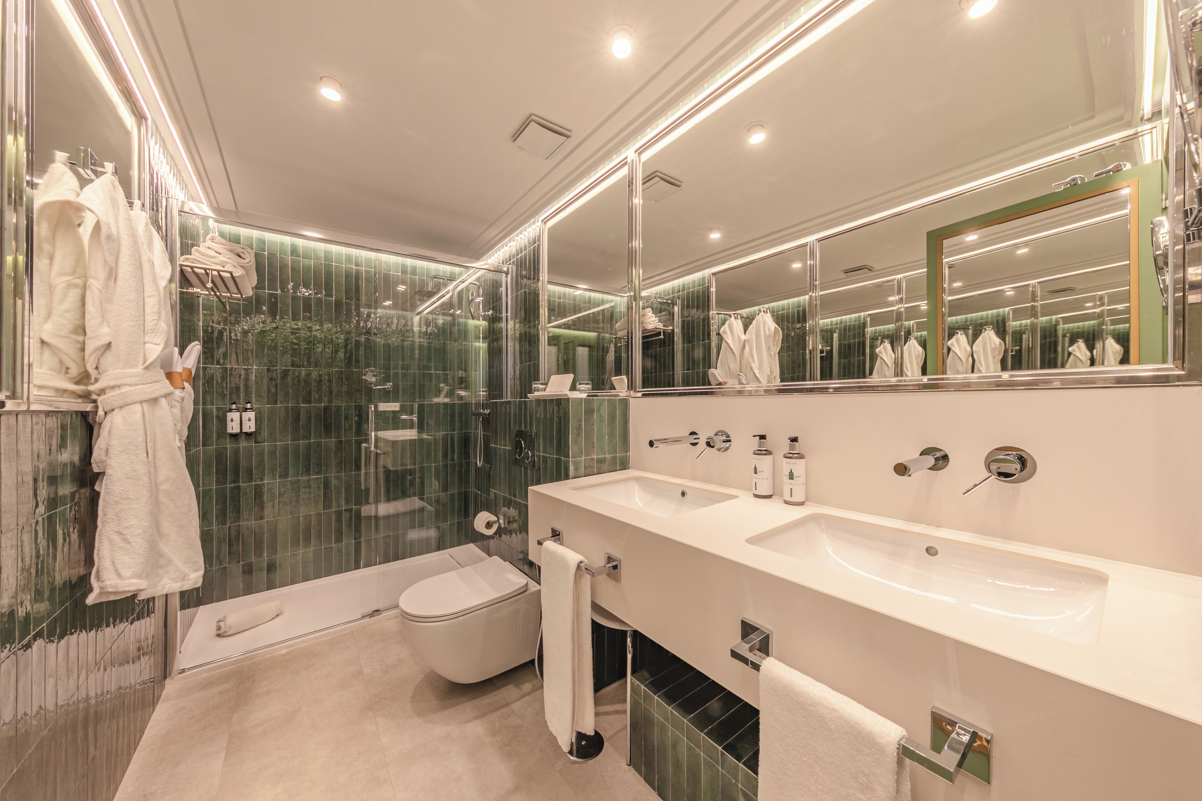 A modern bathroom with two sinks, a large mirror, and a glass shower enclosure.