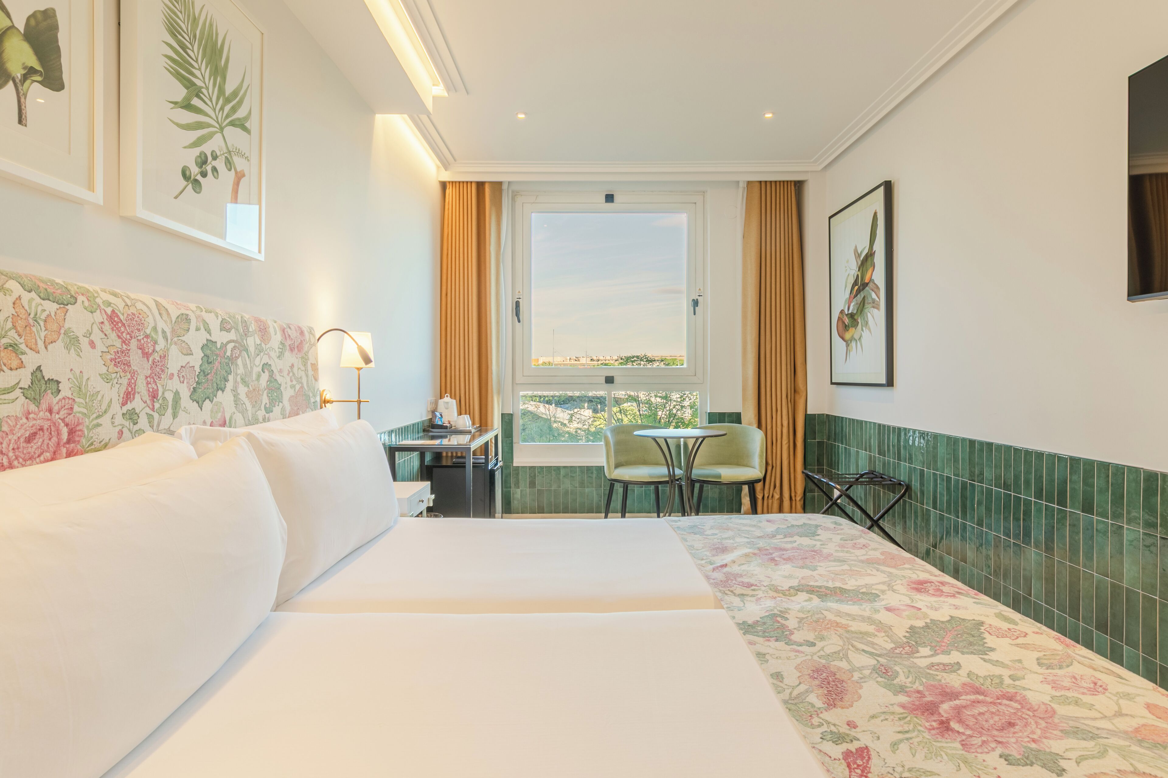 A hotel room with a large bed, a desk with a chair, a small table, and a window with a view.