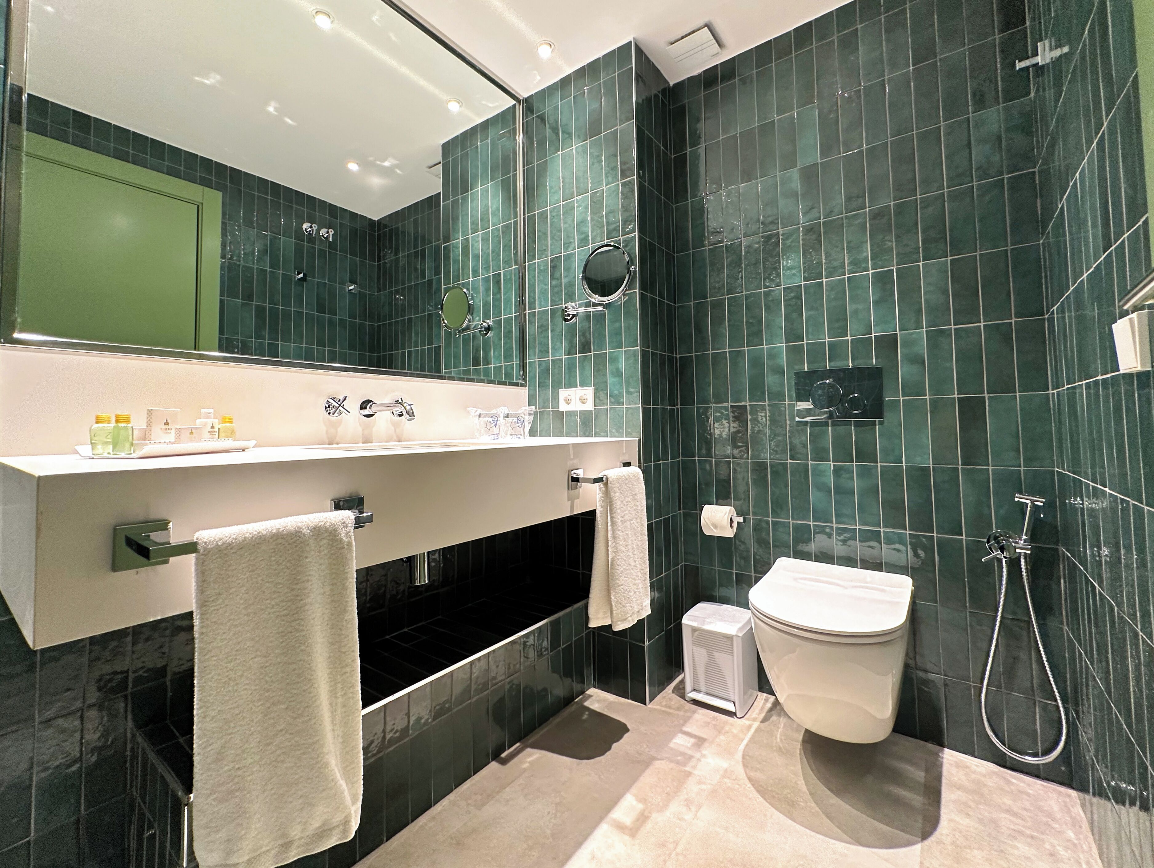 A modern bathroom with a vanity, sink, mirror, and a toilet.