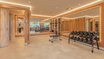 Un gimnasio moderno con equipo de ejercicio, espejos y una barra de mancuernas.
