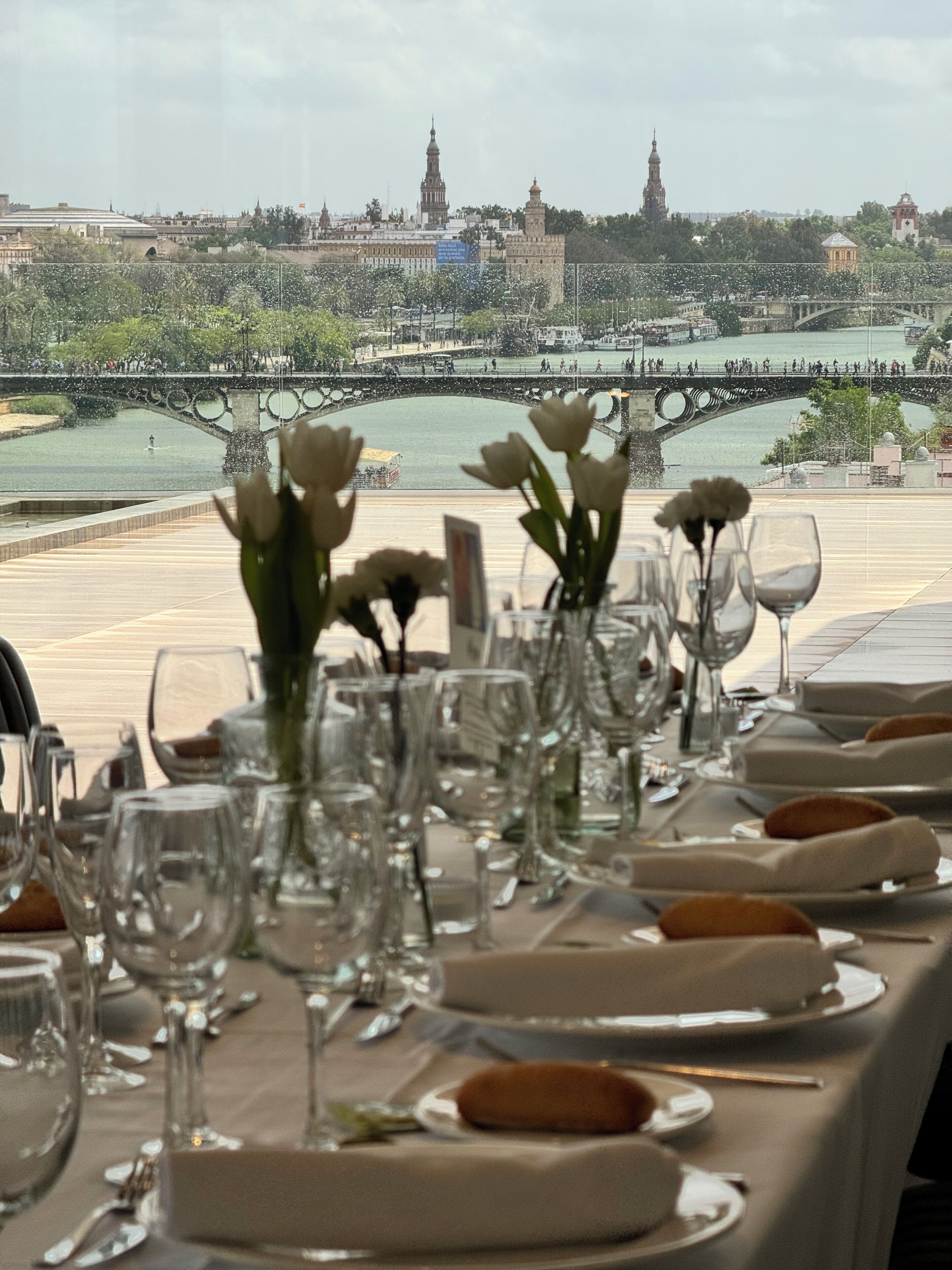 Una mesa dispuesta para comer con vistas a un paisaje urbano histórico y un río.