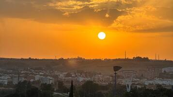 Un atardecer sobre un paisaje urbano con edificios, árboles y una torre destacada.