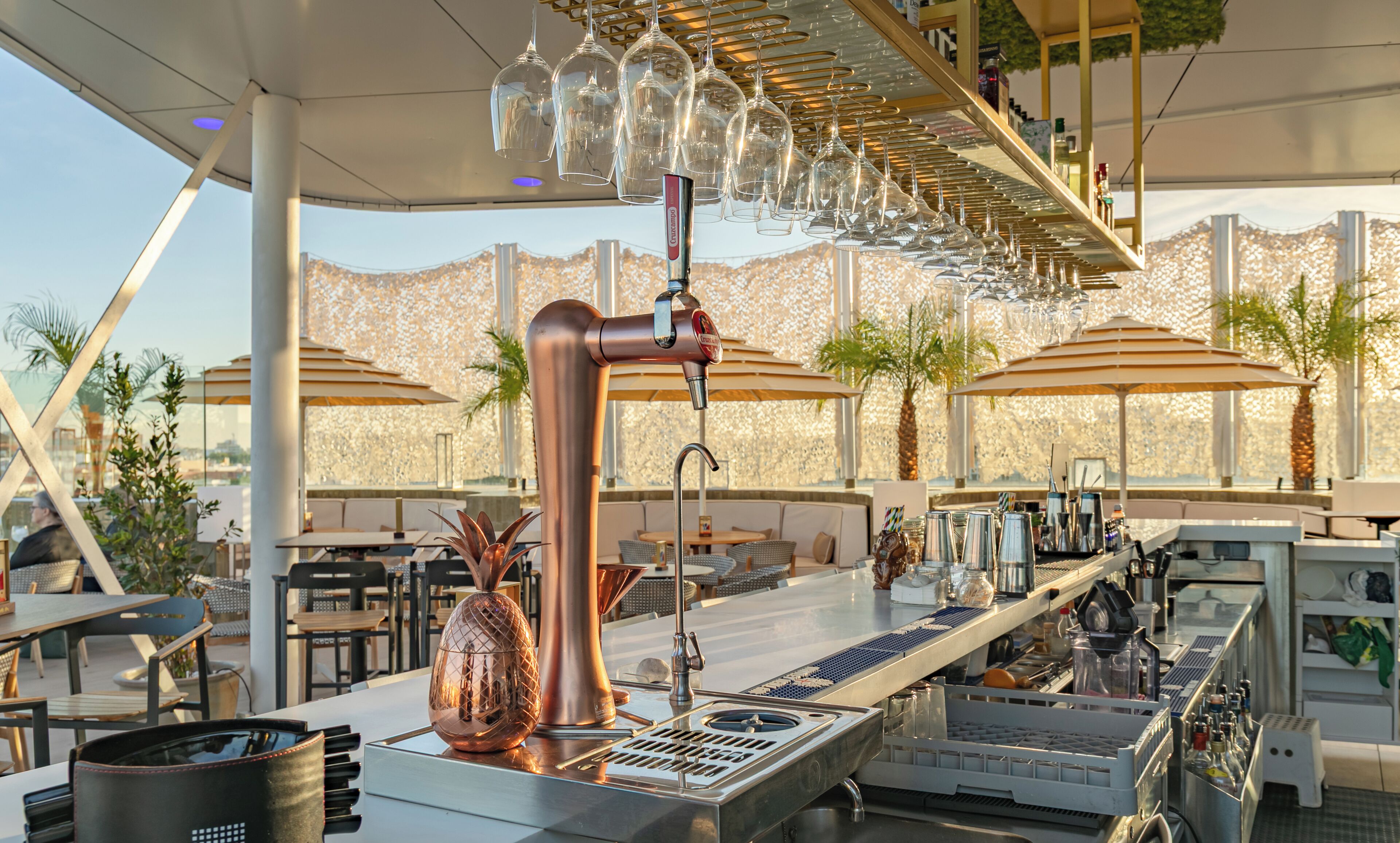 A bar area with a copper tap, seating, and umbrellas.