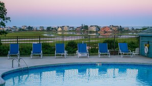 Piscina con sillones de descanso y vista a una zona residencial.