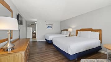 Ein Hotelzimmer mit zwei Betten, einem Schreibtisch, einem Stuhl, einem Fernseher und einem Bild an der Wand.