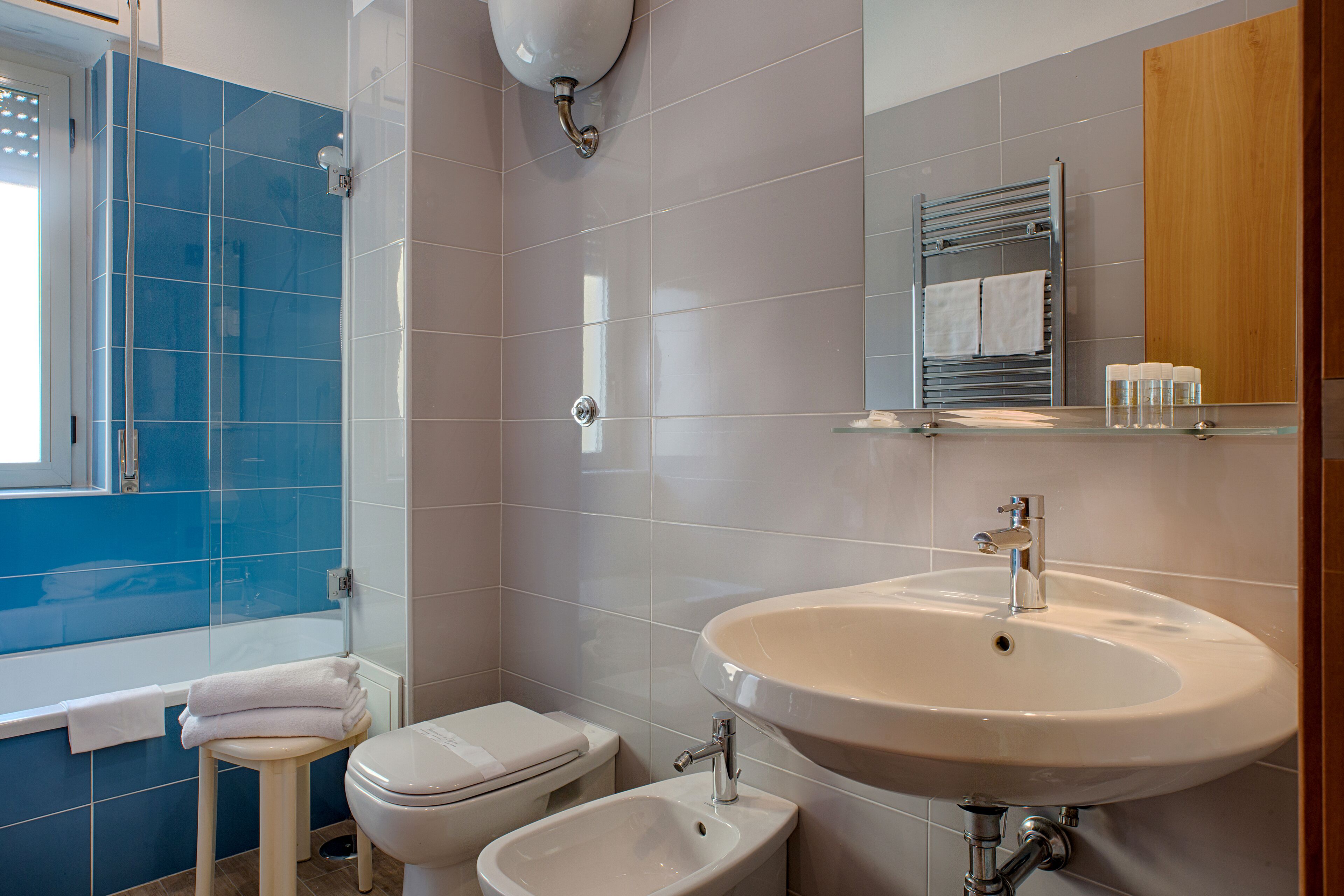 A bathroom with a bathtub, toilet, bidet, sink, and mirror.