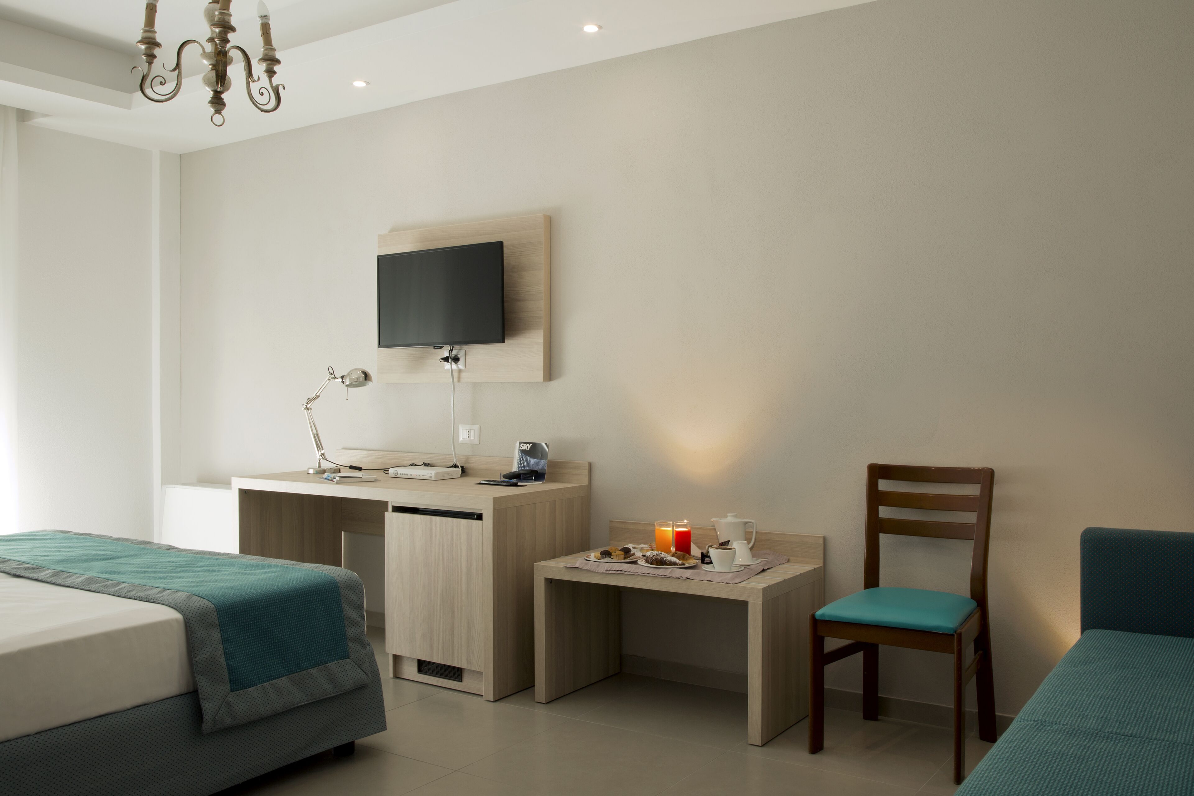 A hotel room with two beds, a desk with a computer, a chair, and a TV mounted on the wall.