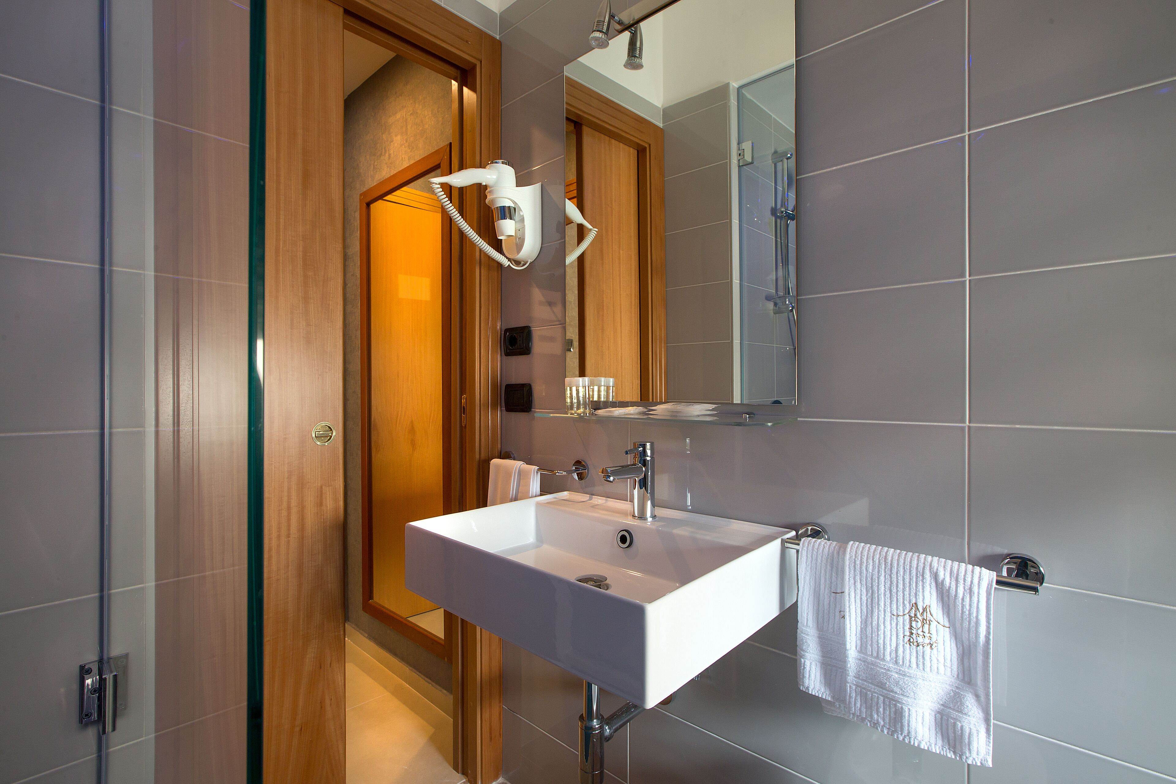 A modern bathroom with a white sink, a mirror, and a towel rack.