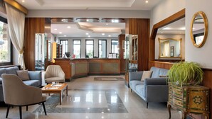 A hotel lobby with a reception desk, seating area, and large windows. - American Hotel (Pozzuoli)