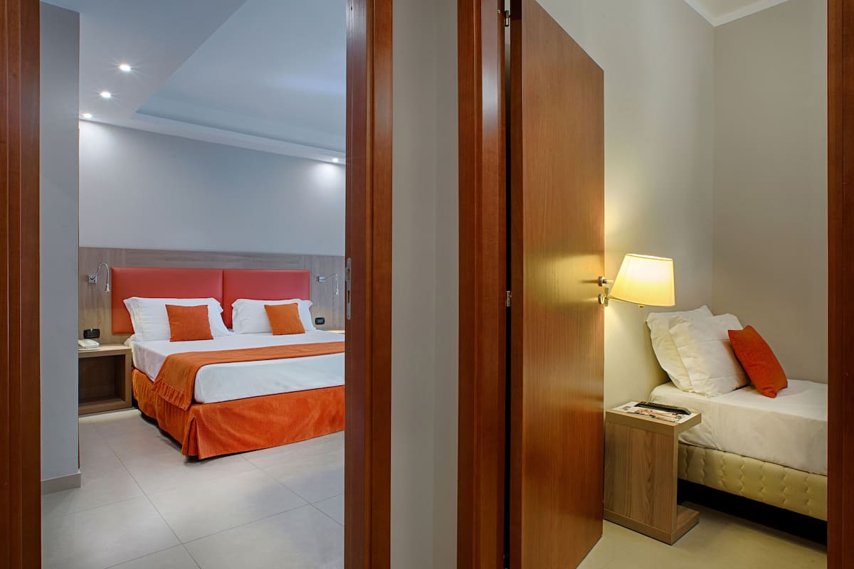 A hotel room with a bed, bedside table, lamp, and a nightstand.