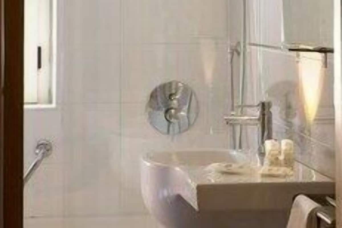 A bathroom with a glass shower enclosure, a sink with a mirror, and a towel rack.