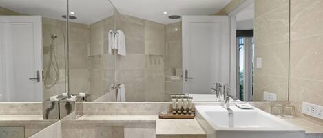 A modern bathroom with a large mirror, a shower, and a sink.