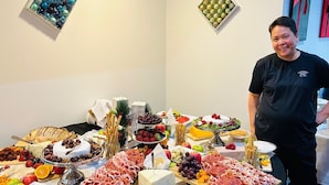 Une table de buffet proposant une variété d’aliments, notamment des viandes, des fromages, des fruits et des légumes.