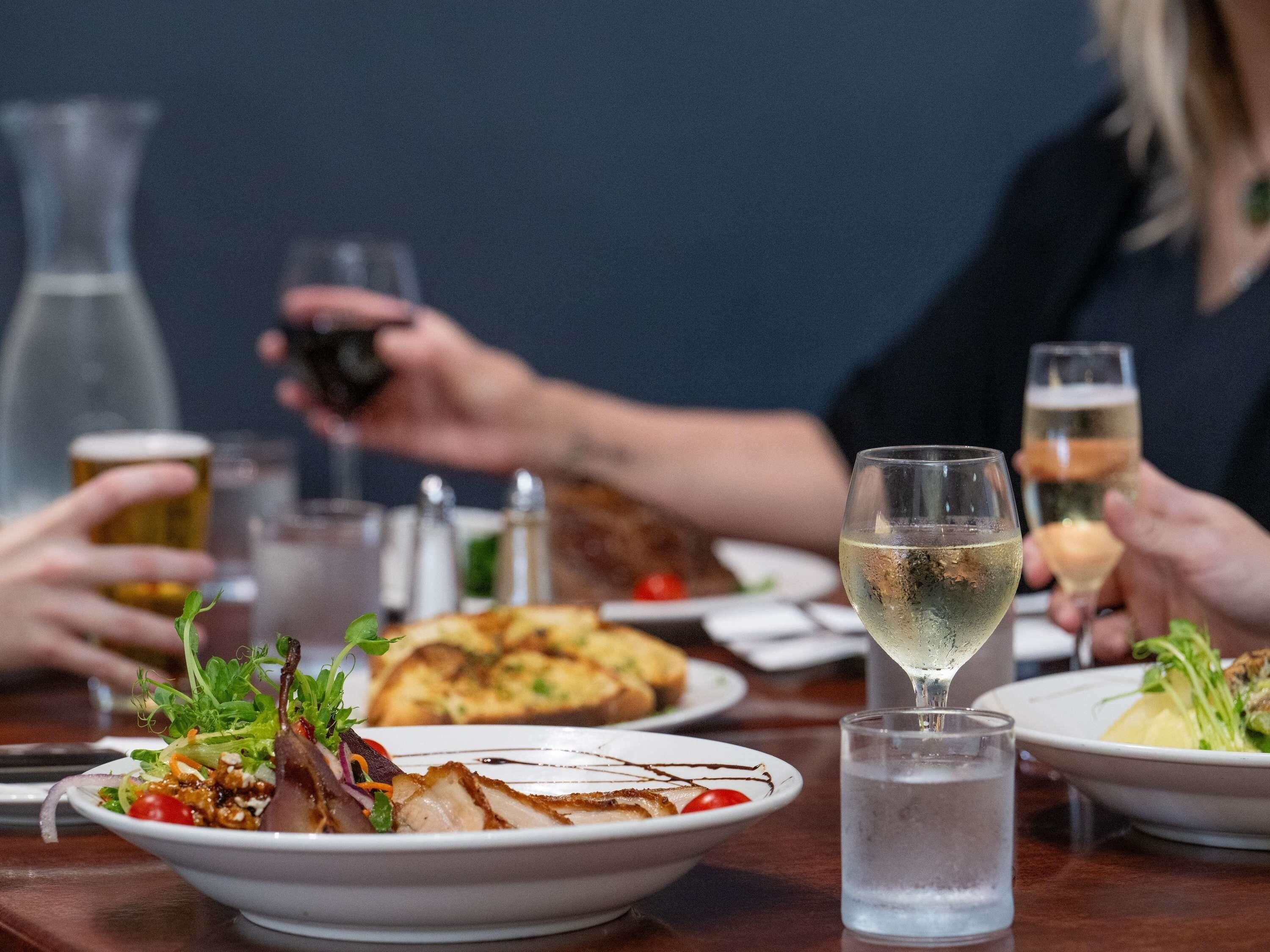 Une table à manger avec différents plats, des verres remplis de boissons et une bouteille.