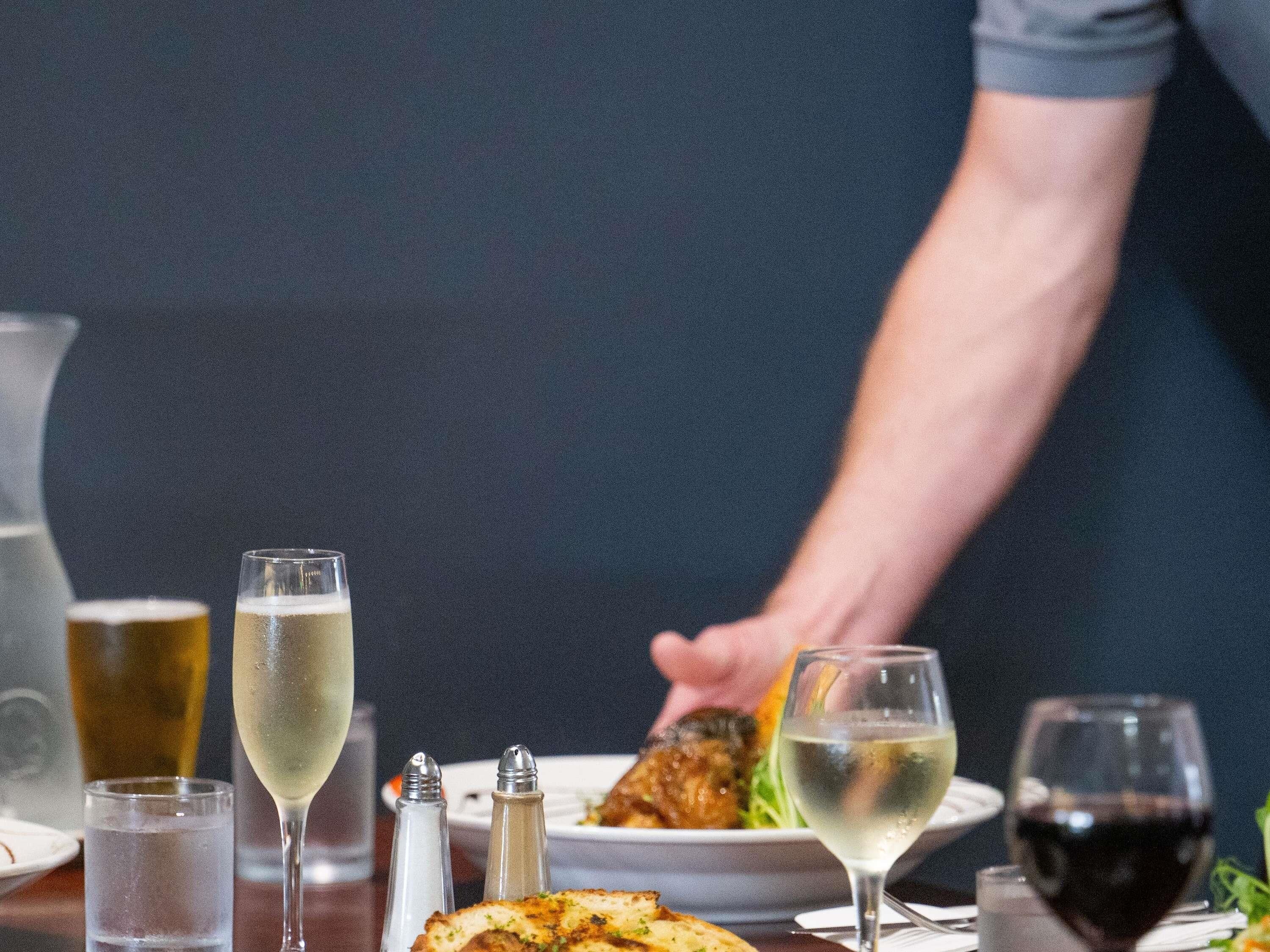 Une table à manger avec différents plats, des verres de vin, et des salières et poivrières.