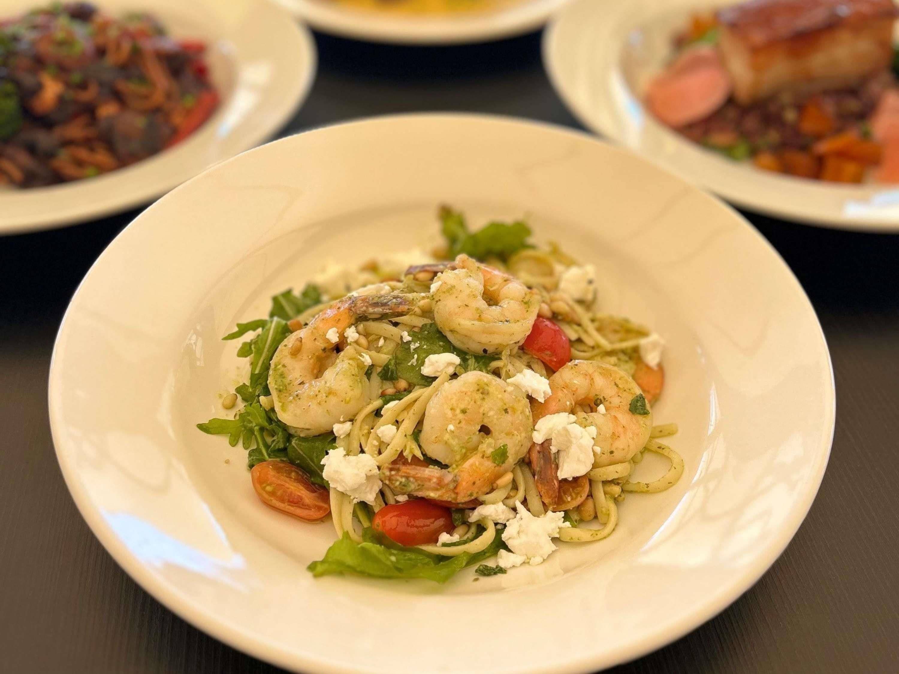 A plate of pasta with shrimp, tomatoes, and cheese.