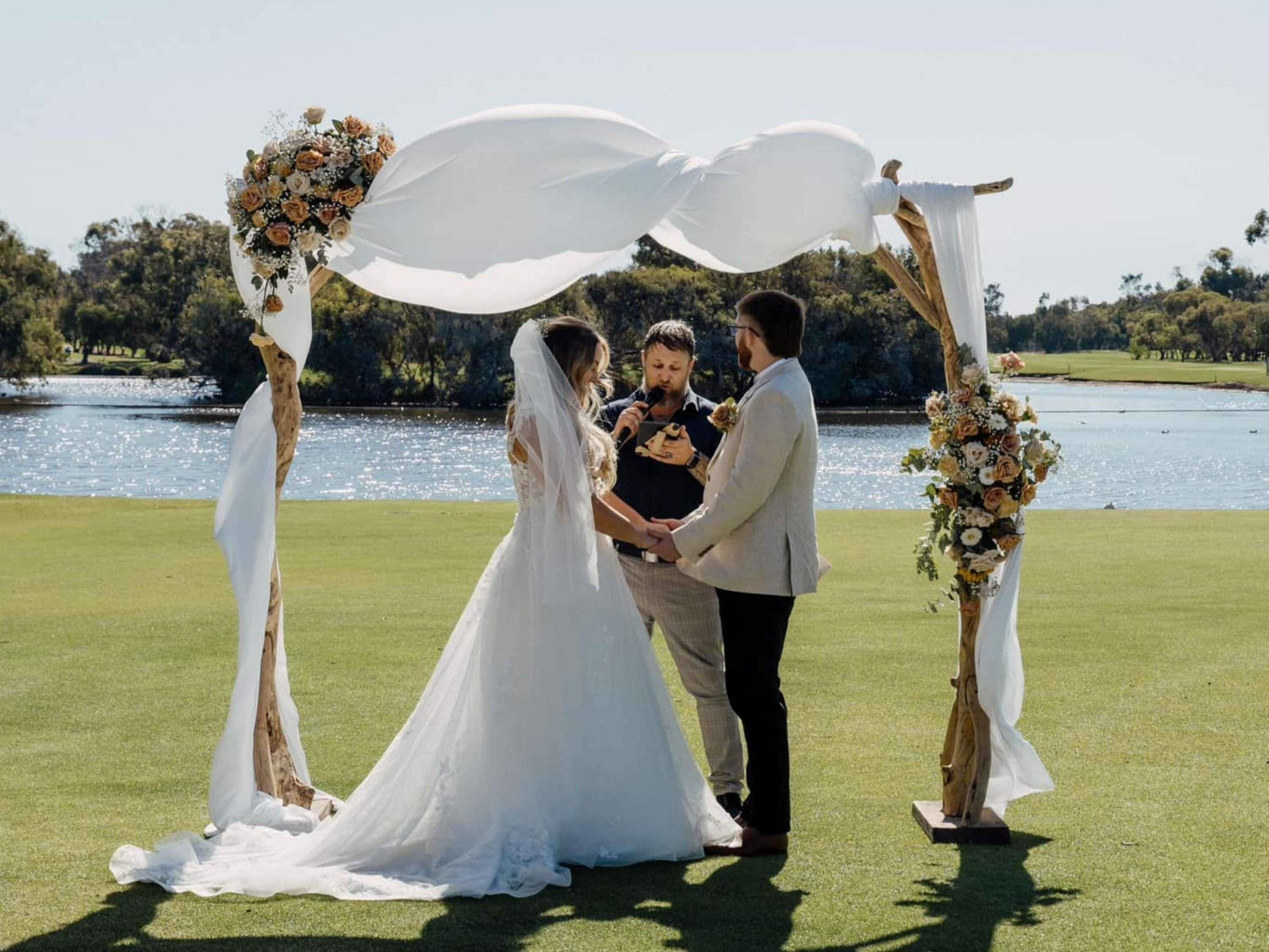 A wedding ceremony on a golf course with a lake in the background.