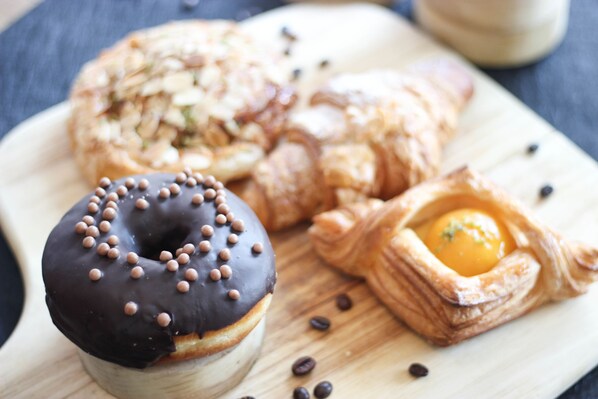 A variety of pastries including a chocolate-covered donut, a croissant, and a pastry with an egg yolk.