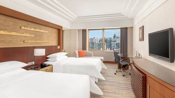Une chambre d’hôtel avec deux lits, un bureau, une télévision et une vue sur la ville.