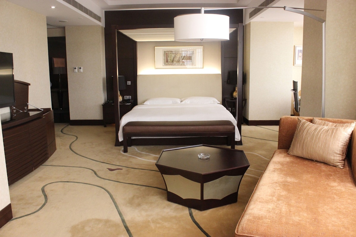 Una habitación de hotel con una cama, un sofá, una mesa de centro y un televisor.