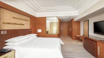 A hotel room with a large bed, a TV, a mirror, and a wooden wardrobe.