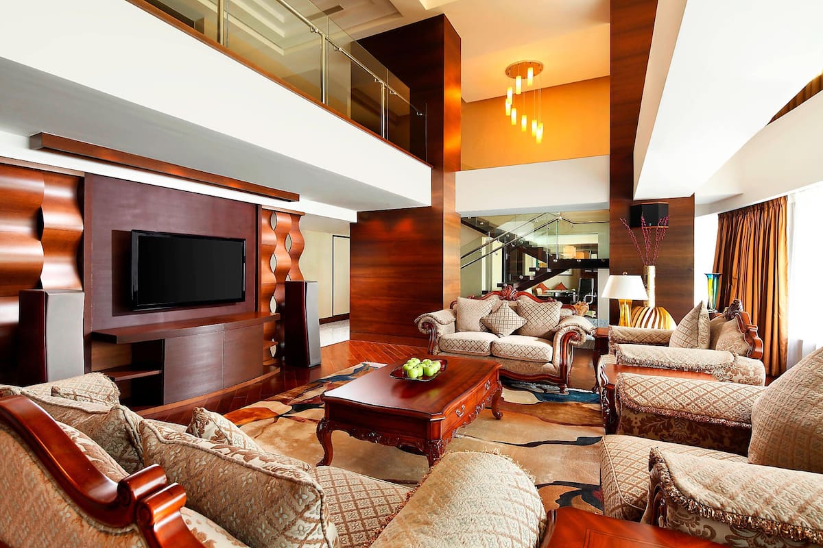 A spacious living area with a large flat-screen TV, comfortable seating, a wooden coffee table, and a staircase leading to an upper level.