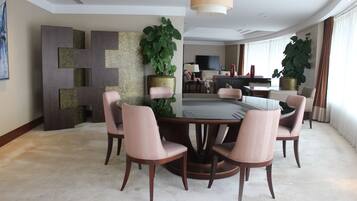 Un comedor moderno con una mesa redonda rodeada por seis sillas, una planta grande en maceta y un diseño contemporáneo en la pared.