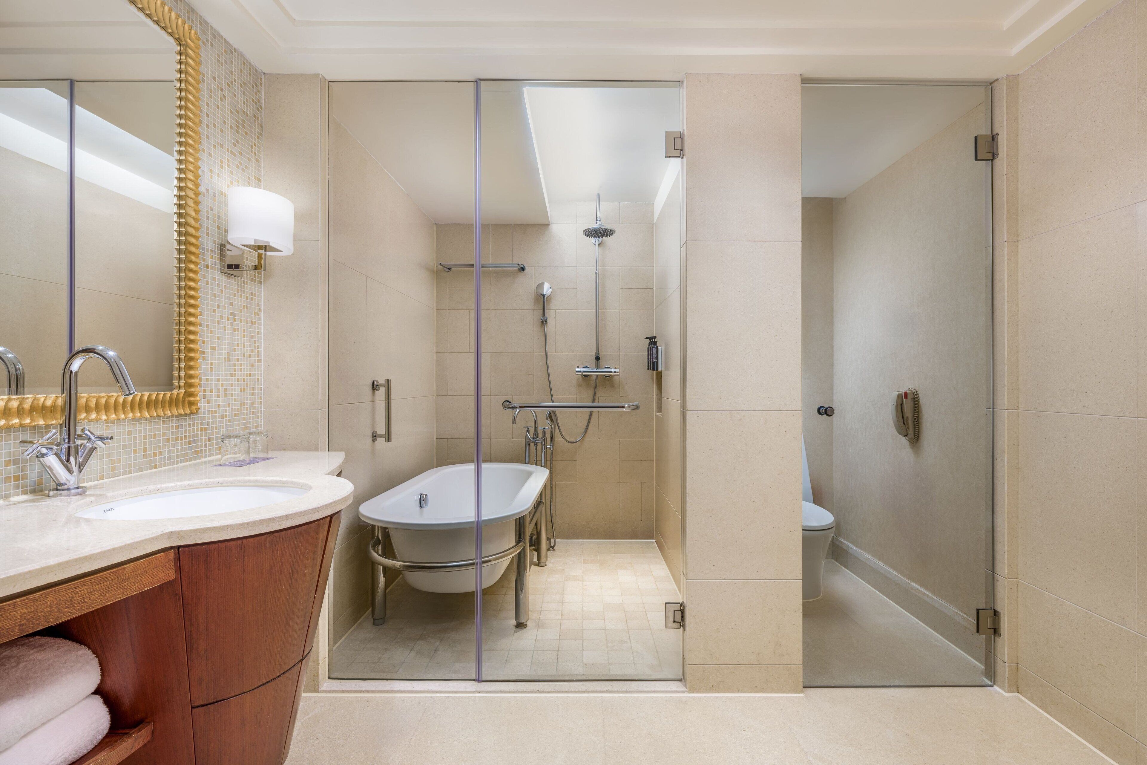 A modern bathroom with a glass-enclosed shower, a freestanding bathtub, and a vanity with a mirror and towel rack.